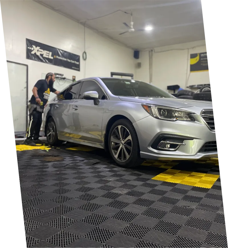 Brandon working on the rear window of a Subaru inside the tint shop