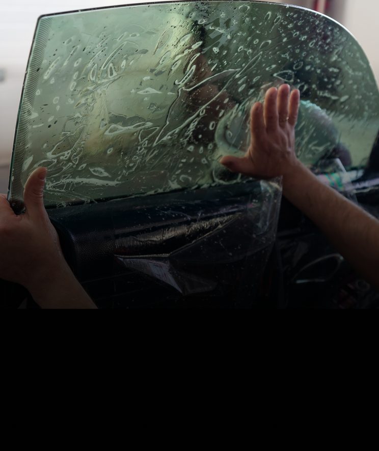 A car window in the process of being tinted by a professional installer